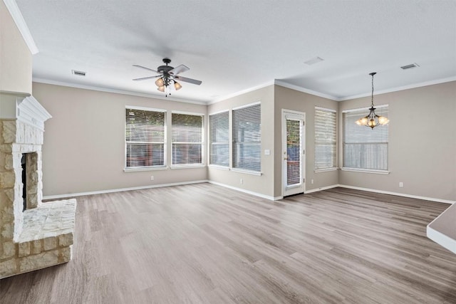 unfurnished living room with hardwood / wood-style floors, ceiling fan with notable chandelier, ornamental molding, a fireplace, and a textured ceiling