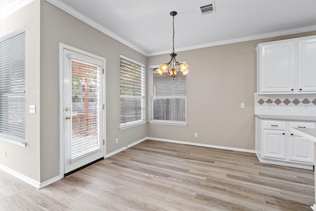 unfurnished dining area featuring ornamental molding, light hardwood / wood-style floors, and a notable chandelier