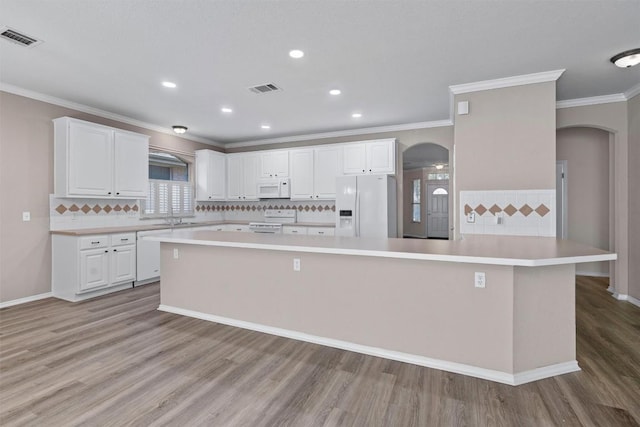 kitchen featuring ornamental molding, white appliances, a spacious island, light hardwood / wood-style flooring, and white cabinetry