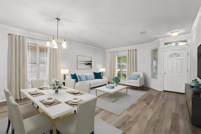 dining area featuring hardwood / wood-style flooring, an inviting chandelier, and crown molding