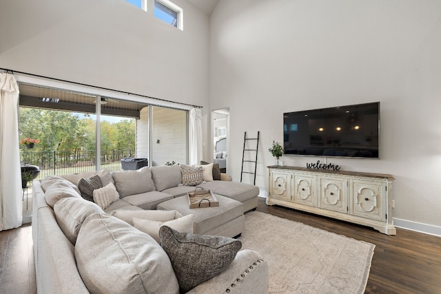 living room with a towering ceiling, dark hardwood / wood-style floors, and a healthy amount of sunlight