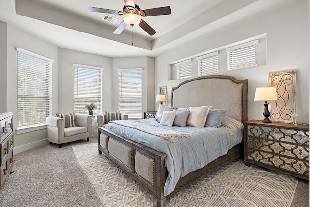 bedroom featuring light carpet, a tray ceiling, and ceiling fan