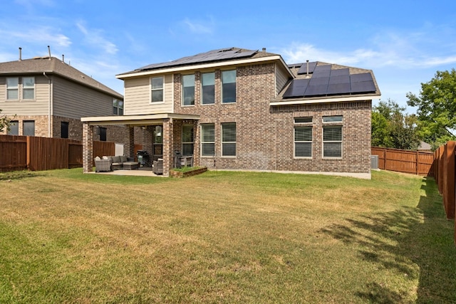 back of house featuring an outdoor living space, a patio area, solar panels, and a yard