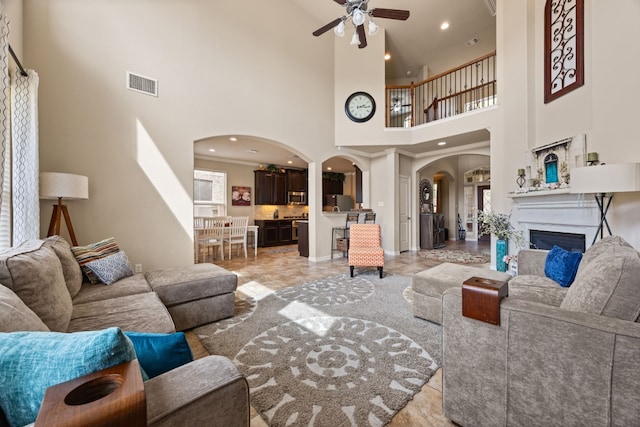 living room with ceiling fan and a towering ceiling