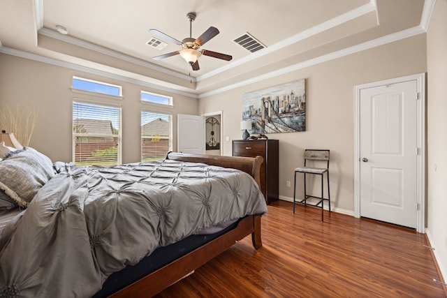 bedroom featuring dark wood-type flooring, a tray ceiling, ceiling fan, and crown molding