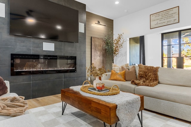 living room featuring wood-type flooring, tile walls, and a tiled fireplace