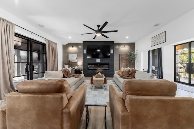 living room with ceiling fan, lofted ceiling, wooden walls, a fireplace, and hardwood / wood-style floors