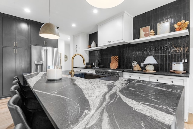 kitchen with dark stone counters, light hardwood / wood-style floors, tasteful backsplash, sink, and appliances with stainless steel finishes