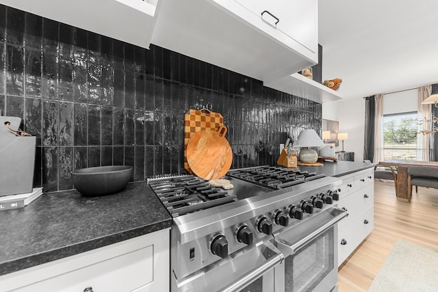 kitchen with decorative backsplash, high end stainless steel range oven, light hardwood / wood-style flooring, and white cabinets