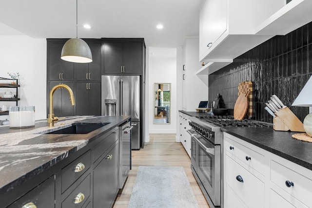 kitchen with hanging light fixtures, high quality appliances, sink, and white cabinets