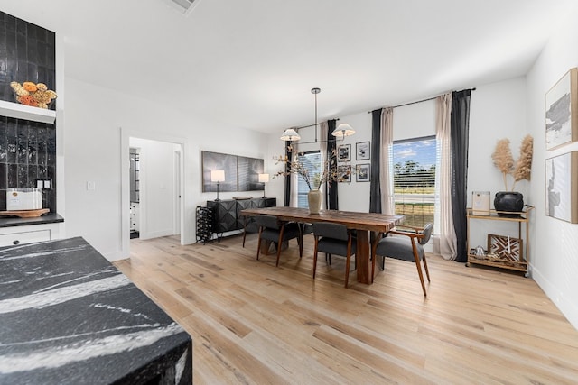 dining area featuring light hardwood / wood-style flooring and a notable chandelier