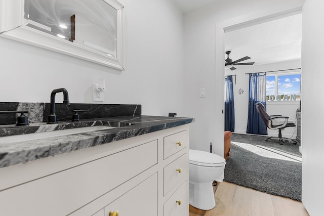 bathroom featuring ceiling fan, hardwood / wood-style flooring, vanity, and toilet