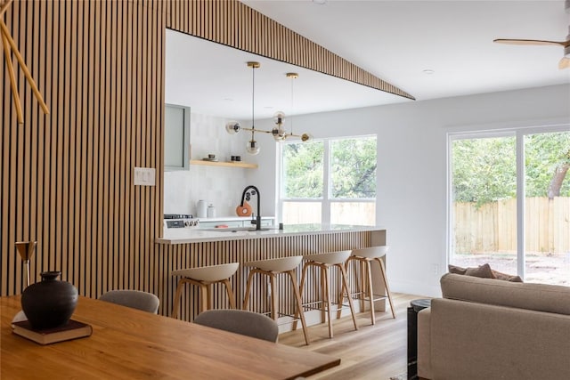 kitchen featuring a breakfast bar, decorative light fixtures, a healthy amount of sunlight, and sink