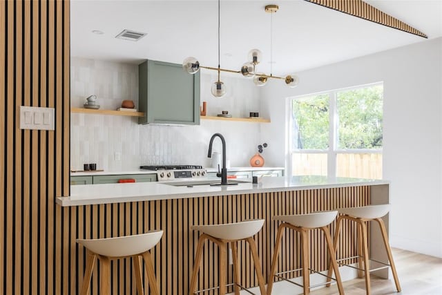 kitchen with tasteful backsplash, hanging light fixtures, green cabinets, and a breakfast bar area