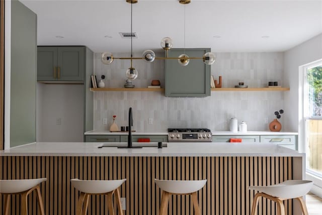 kitchen with pendant lighting, a kitchen breakfast bar, stove, and backsplash