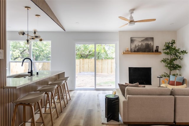 living room featuring ceiling fan, sink, plenty of natural light, and light wood-type flooring