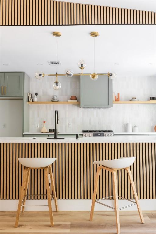 bar with hardwood / wood-style flooring, decorative backsplash, sink, and hanging light fixtures