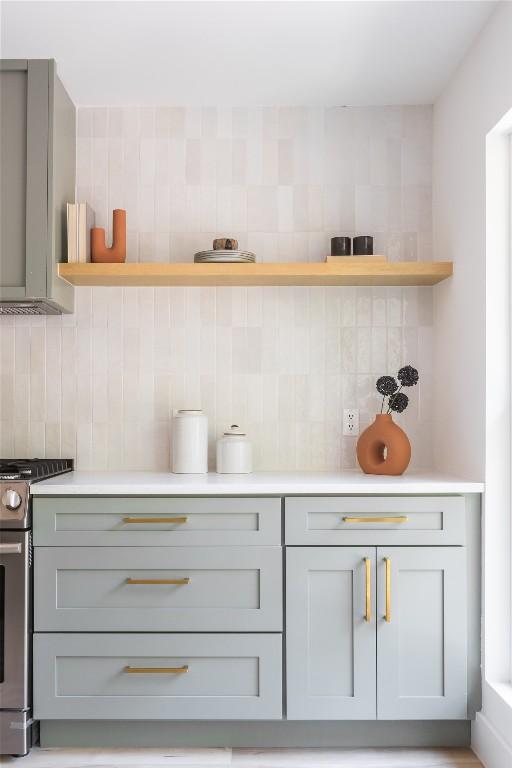 kitchen featuring gas range, decorative backsplash, and gray cabinets