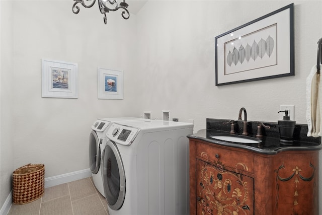 washroom with washing machine and clothes dryer, an inviting chandelier, and sink