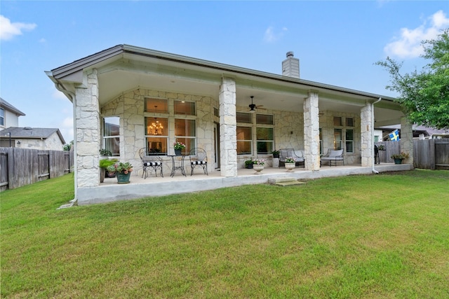 rear view of property with ceiling fan, a lawn, and a patio area