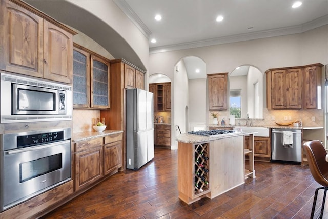 4408 Blacksmith Cv, Spicewood, TX 78669 - kitchen featuring stainless steel appliances, crown molding, a kitchen island, glass insert cabinets, and backsplash