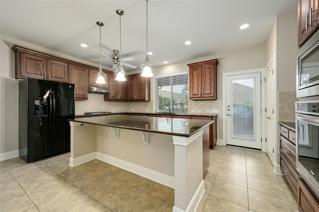 kitchen featuring a kitchen breakfast bar, ceiling fan, decorative light fixtures, a kitchen island, and stainless steel appliances