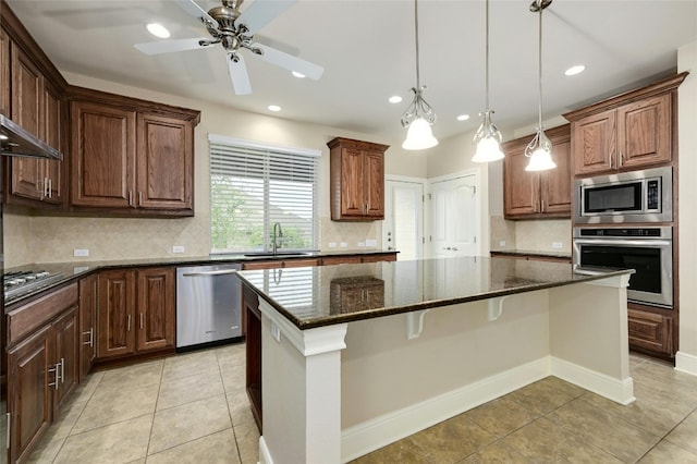 kitchen with a center island, sink, appliances with stainless steel finishes, and dark stone counters