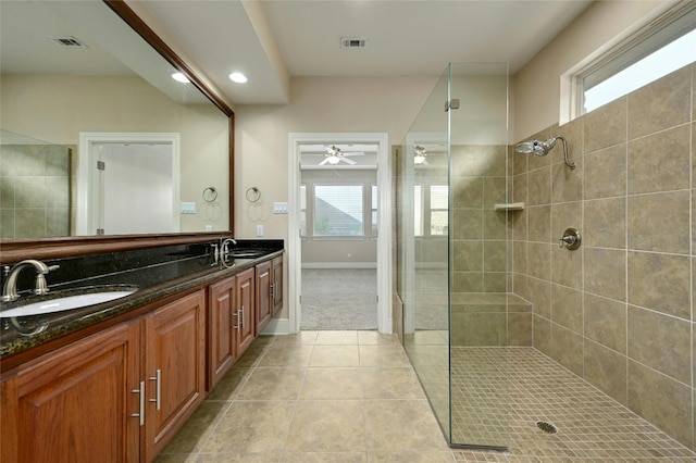 bathroom with tile patterned floors, vanity, a healthy amount of sunlight, and tiled shower