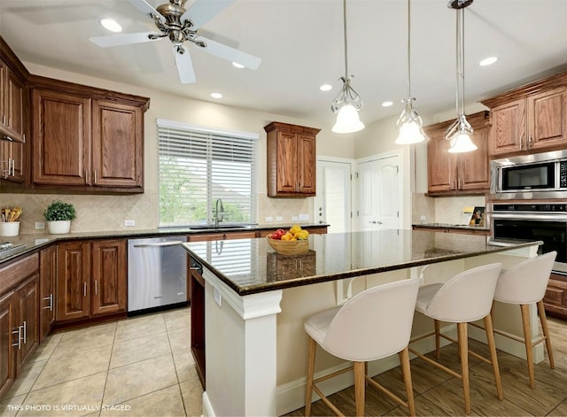 kitchen featuring a center island, dark stone countertops, sink, and appliances with stainless steel finishes