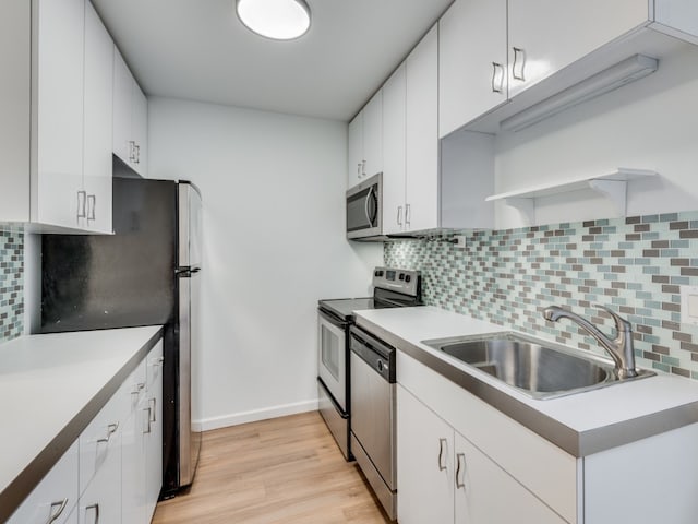 kitchen featuring backsplash, sink, stainless steel appliances, and white cabinets