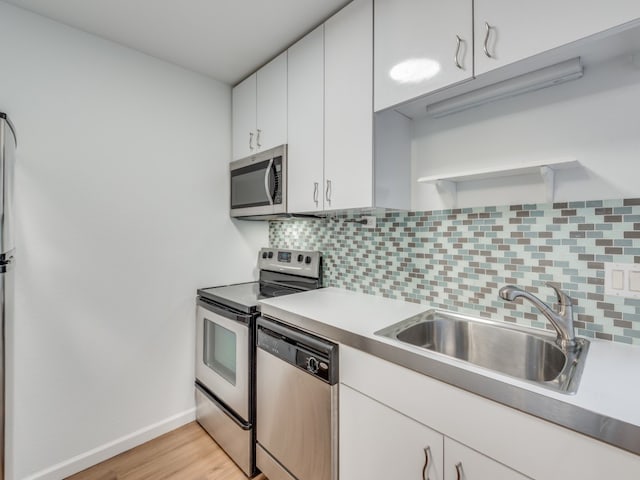 kitchen with white cabinetry, tasteful backsplash, stainless steel appliances, light wood-type flooring, and sink