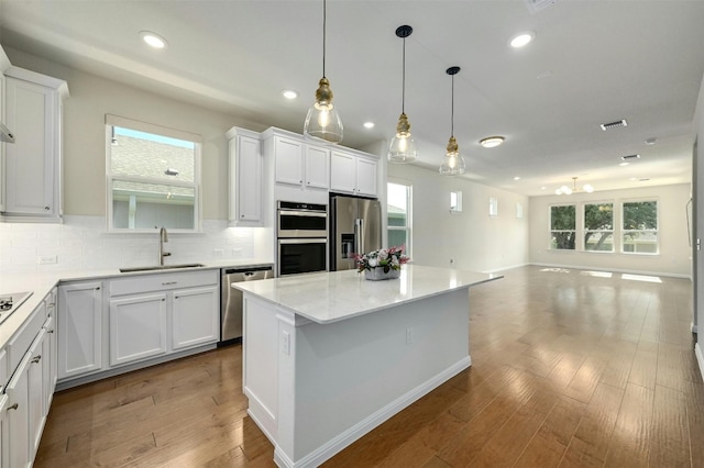 kitchen featuring wood-type flooring, white cabinetry, appliances with stainless steel finishes, and sink