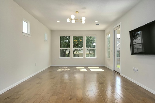 unfurnished room featuring hardwood / wood-style flooring and a notable chandelier