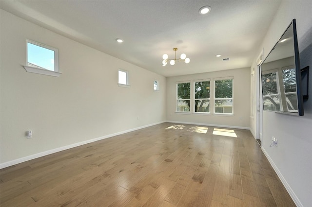 spare room with light hardwood / wood-style flooring and a chandelier