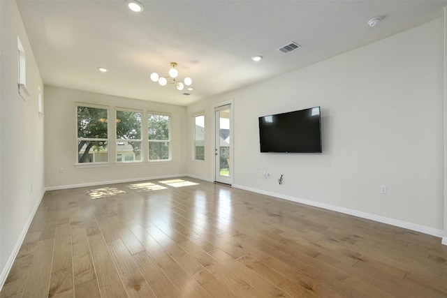 unfurnished living room with light hardwood / wood-style flooring and a notable chandelier