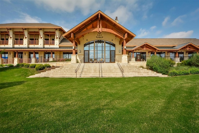 rear view of property featuring a balcony and a lawn