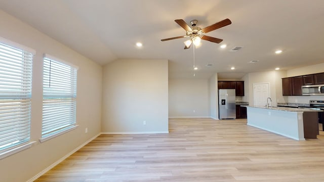 kitchen featuring light stone counters, stainless steel appliances, ceiling fan, light hardwood / wood-style flooring, and sink