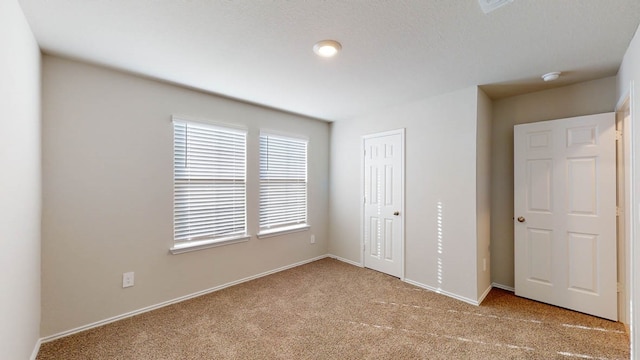 unfurnished bedroom with light colored carpet and a closet