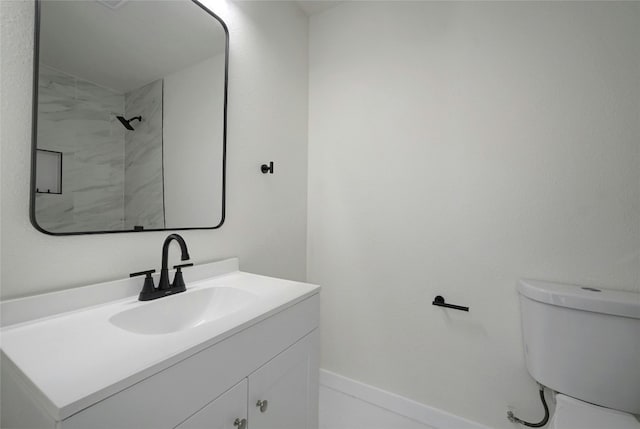 bathroom with tiled shower, vanity, and toilet