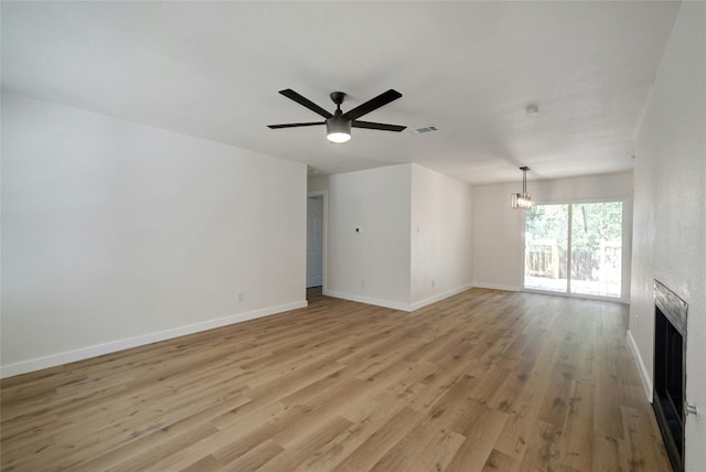 unfurnished living room featuring light hardwood / wood-style flooring and ceiling fan with notable chandelier