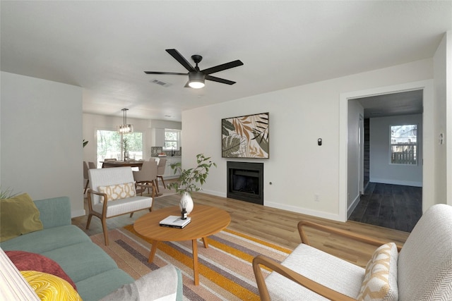 living room featuring ceiling fan with notable chandelier and light hardwood / wood-style floors