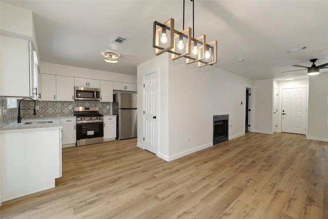 kitchen featuring ceiling fan, white cabinets, pendant lighting, light hardwood / wood-style flooring, and stainless steel appliances