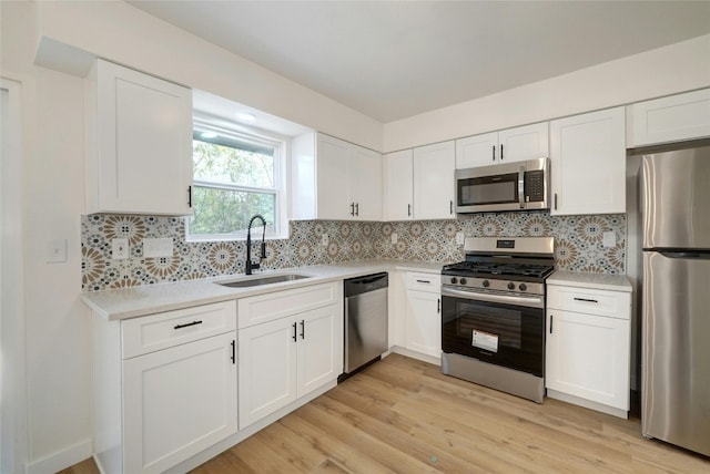 kitchen with decorative backsplash, light wood-type flooring, white cabinets, and appliances with stainless steel finishes