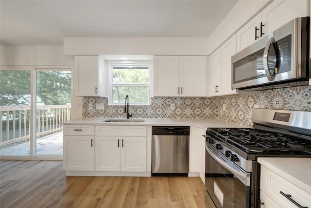 kitchen with appliances with stainless steel finishes, light hardwood / wood-style floors, and white cabinetry