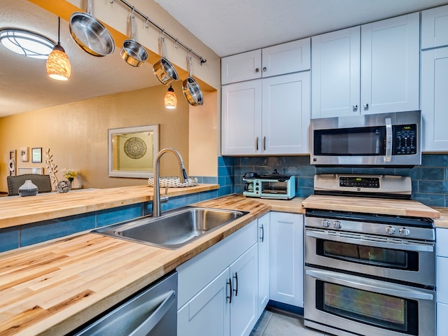 kitchen featuring butcher block countertops, stainless steel appliances, and white cabinets