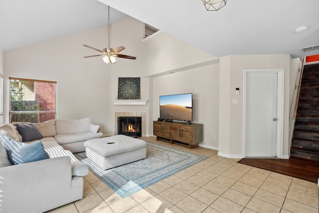 living room featuring ceiling fan, light wood-type flooring, high vaulted ceiling, and a tiled fireplace