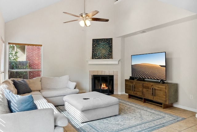 living room featuring a tile fireplace, light tile patterned floors, high vaulted ceiling, and ceiling fan