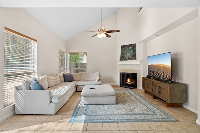 living room featuring ceiling fan, a fireplace, high vaulted ceiling, and light tile patterned floors