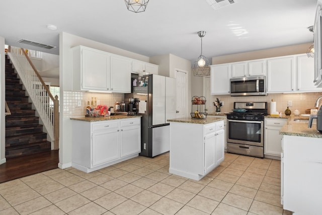 kitchen with decorative backsplash, stainless steel appliances, pendant lighting, white cabinets, and a kitchen island