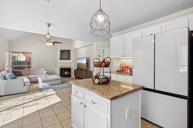 kitchen featuring a center island, white fridge, white cabinetry, and vaulted ceiling